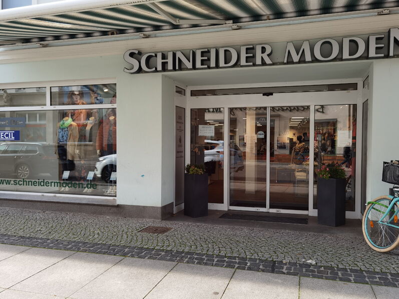 Schaufenster des Ladens Schneider Moden mit Fahrrad im Vordergrund.