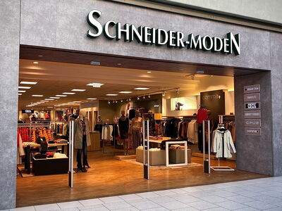 Geschäftseingang von Schneider-Moden mit Kleiderauslagen.