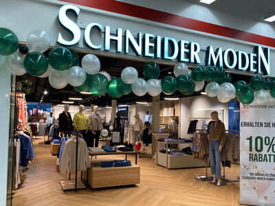 Innenansicht des Schneider Moden Geschäfts mit Ballen und Rabattangebot.