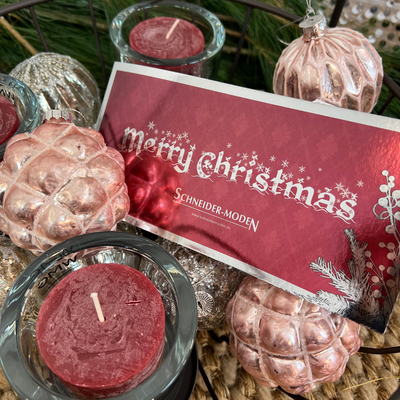Weihnachtliche Dekoration mit Kerzen, Tannenzapfen und einer Karte.