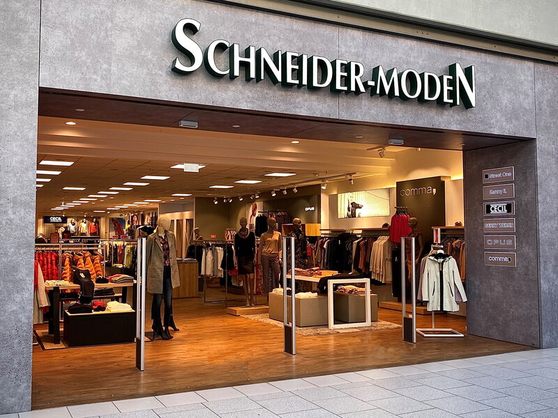 Geschäftseingang von Schneider-Moden mit Kleiderauslagen.